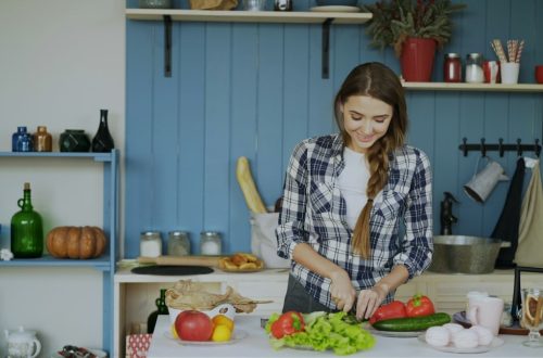 Cheerful young woman cooking breakfast in the kitchen early morning at home