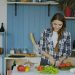 Cheerful young woman cooking breakfast in the kitchen early morning at home