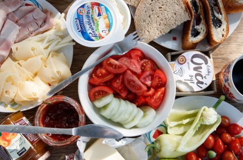 Delicious breakfast setup with cheese, cold cuts, bread, and fresh vegetables.