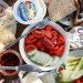 Delicious breakfast setup with cheese, cold cuts, bread, and fresh vegetables.